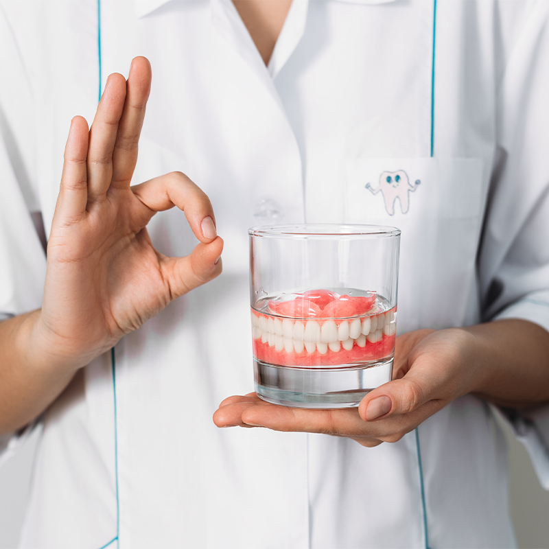 Dentist holding a set of dentures in a glass